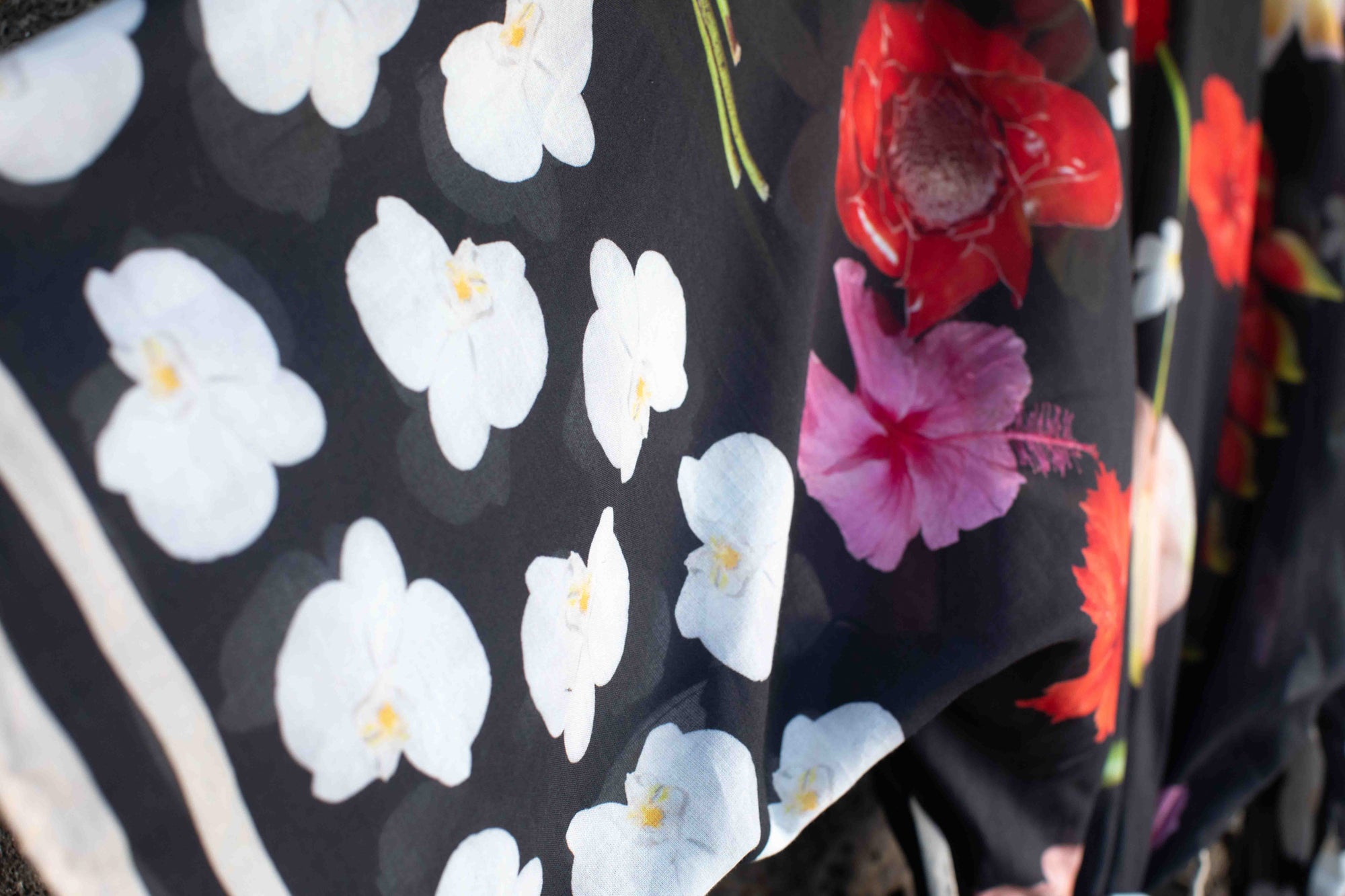 Elegant island kimono wrap with black cotton fabric and bold Hawaiian-inspired flowers including banana blossoms, heliconia, and hibiscus.