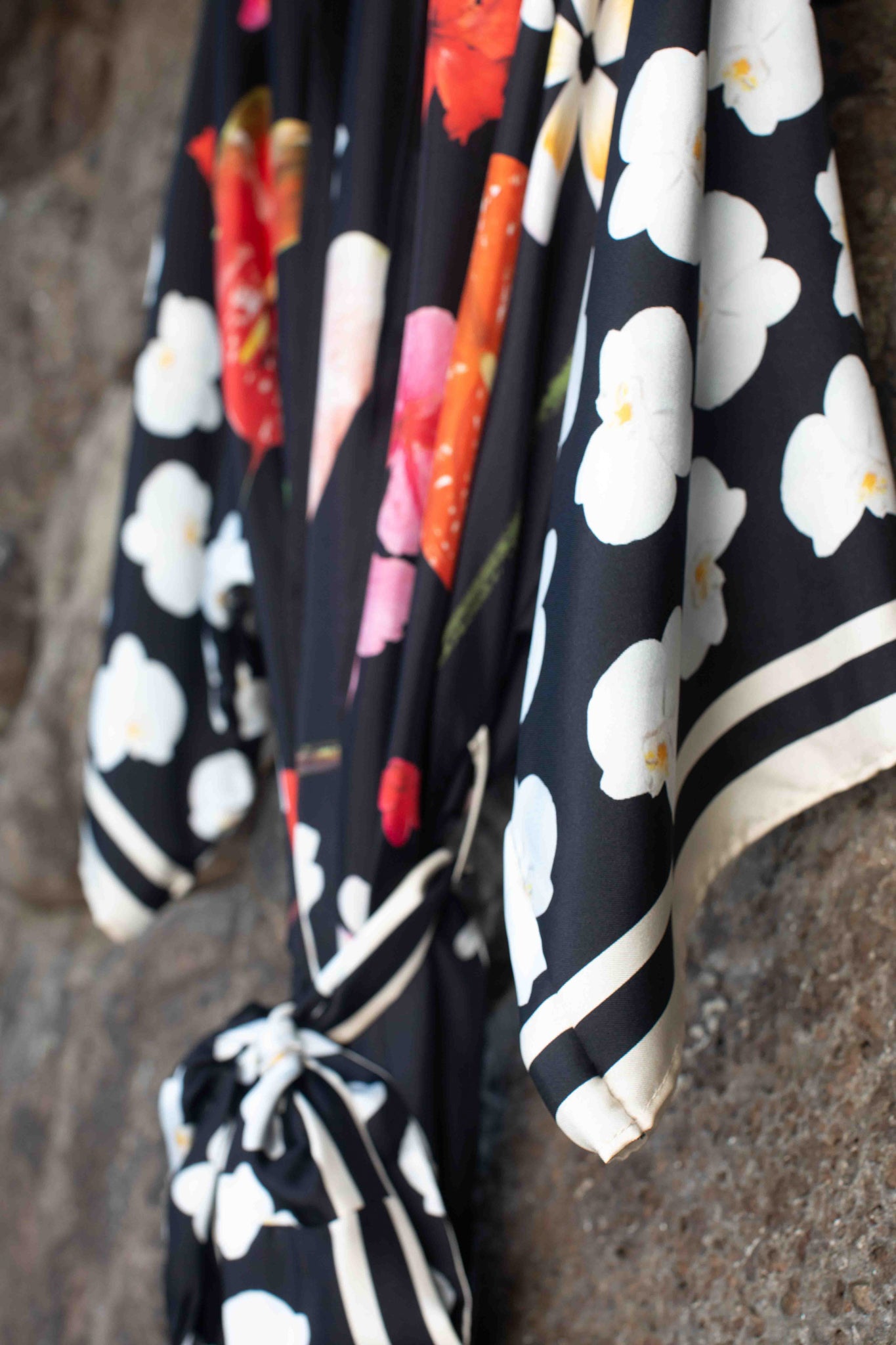 Hawaiian botanical silk kimono robe with luxurious black backdrop and colorful tropical flowers by Lola Pilar, crafted in Italy.