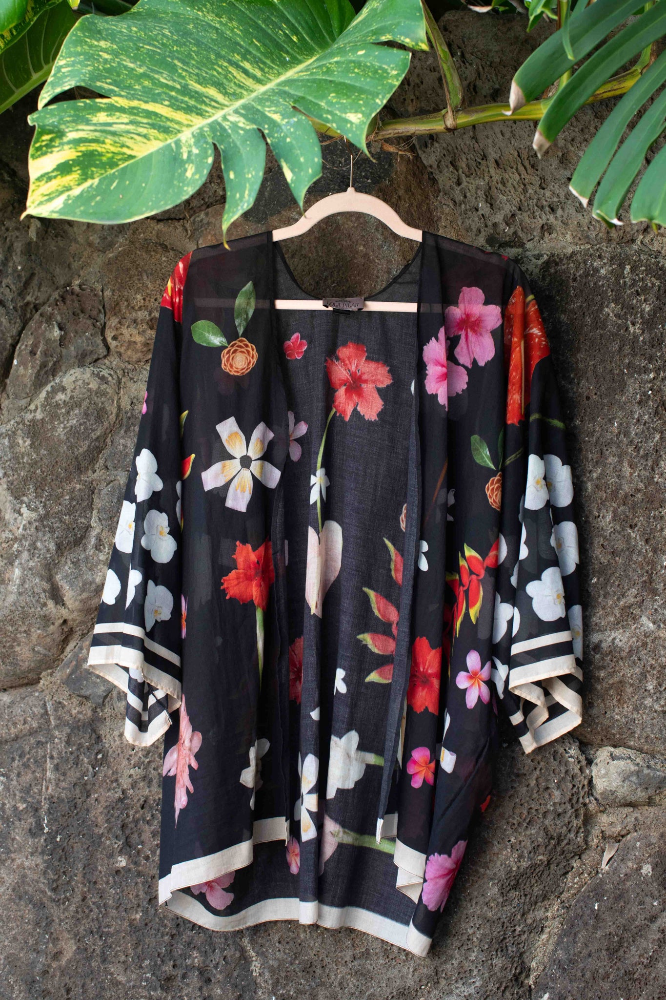 Hawaiian-inspired cotton wrap top with black background and bold hibiscus, hanging heliconia, and plumeria print by Lola Pilar.