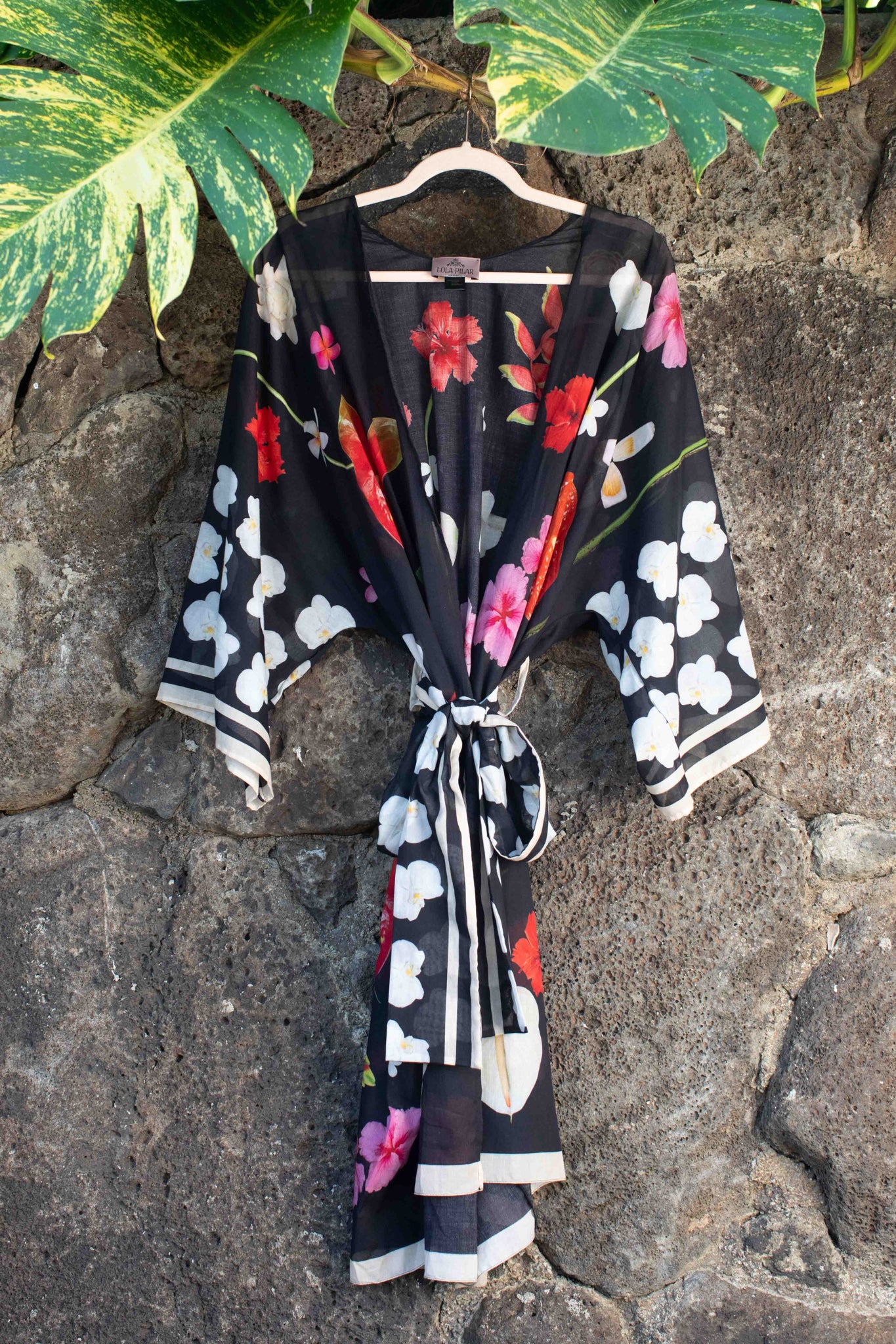 Italian-made black cotton kimono robe with vibrant island botanicals including hibiscus, hanging heliconia, and torch ginger, designed in Hawaii by Lola Pilar.
