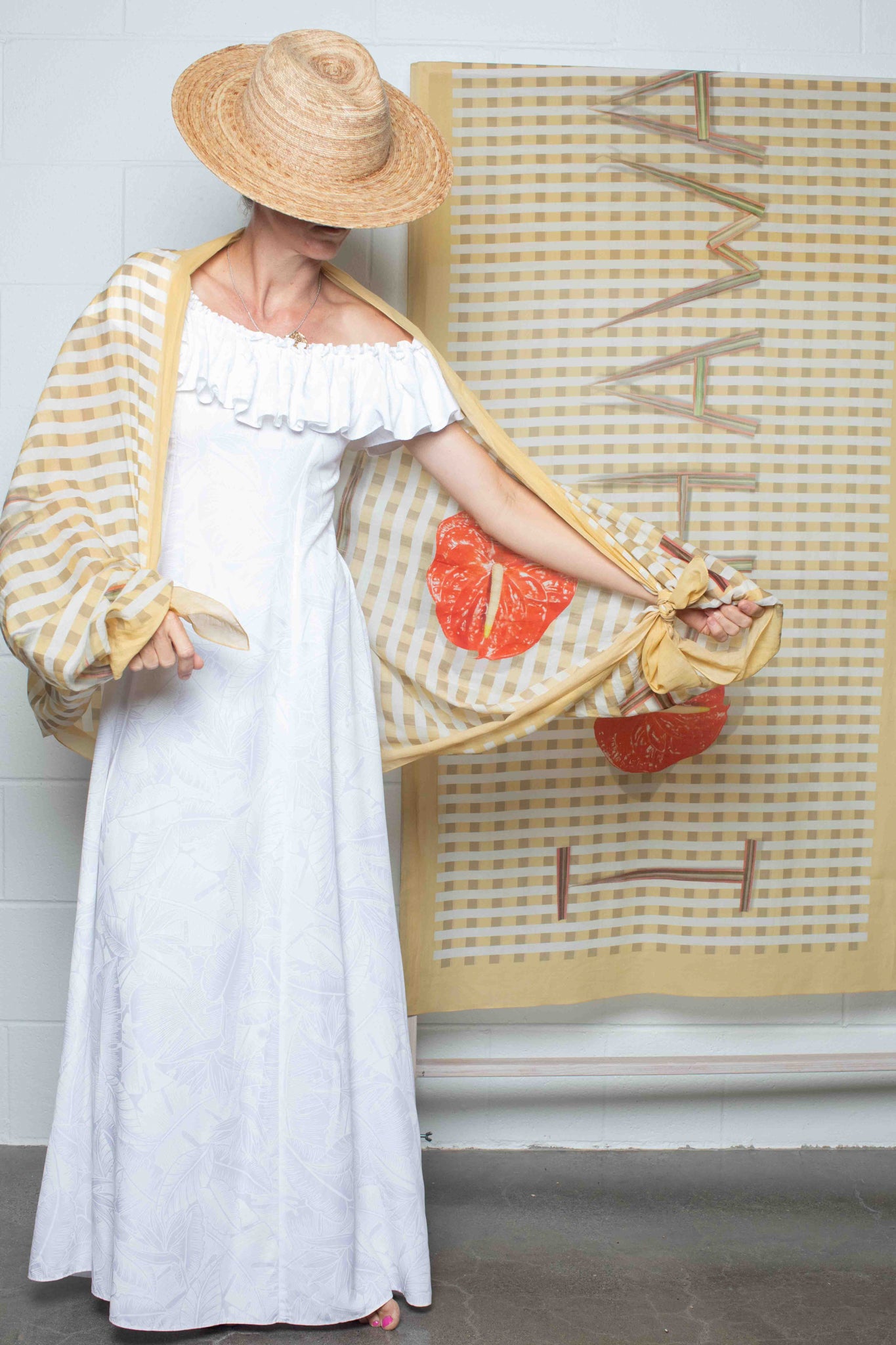 Checkered pareo made in Italy and designed in Hawaii featuring yellow and white patterning with “I Love Hawaii” text and a red anthurium flower Lola Pilar