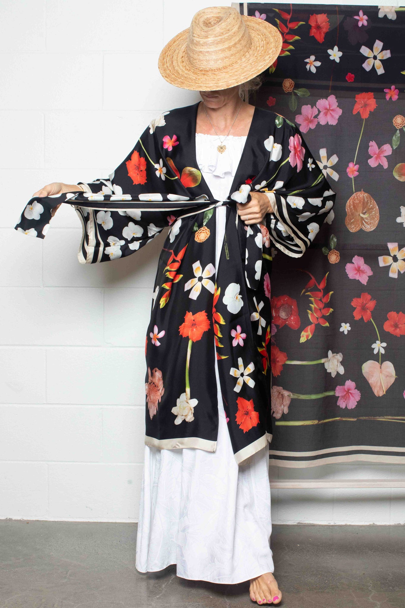 Luxury black silk robe with elegant tropical Hawaiian blooms in vivid pink, yellow, red, and white tones for elevated resort and travel style.