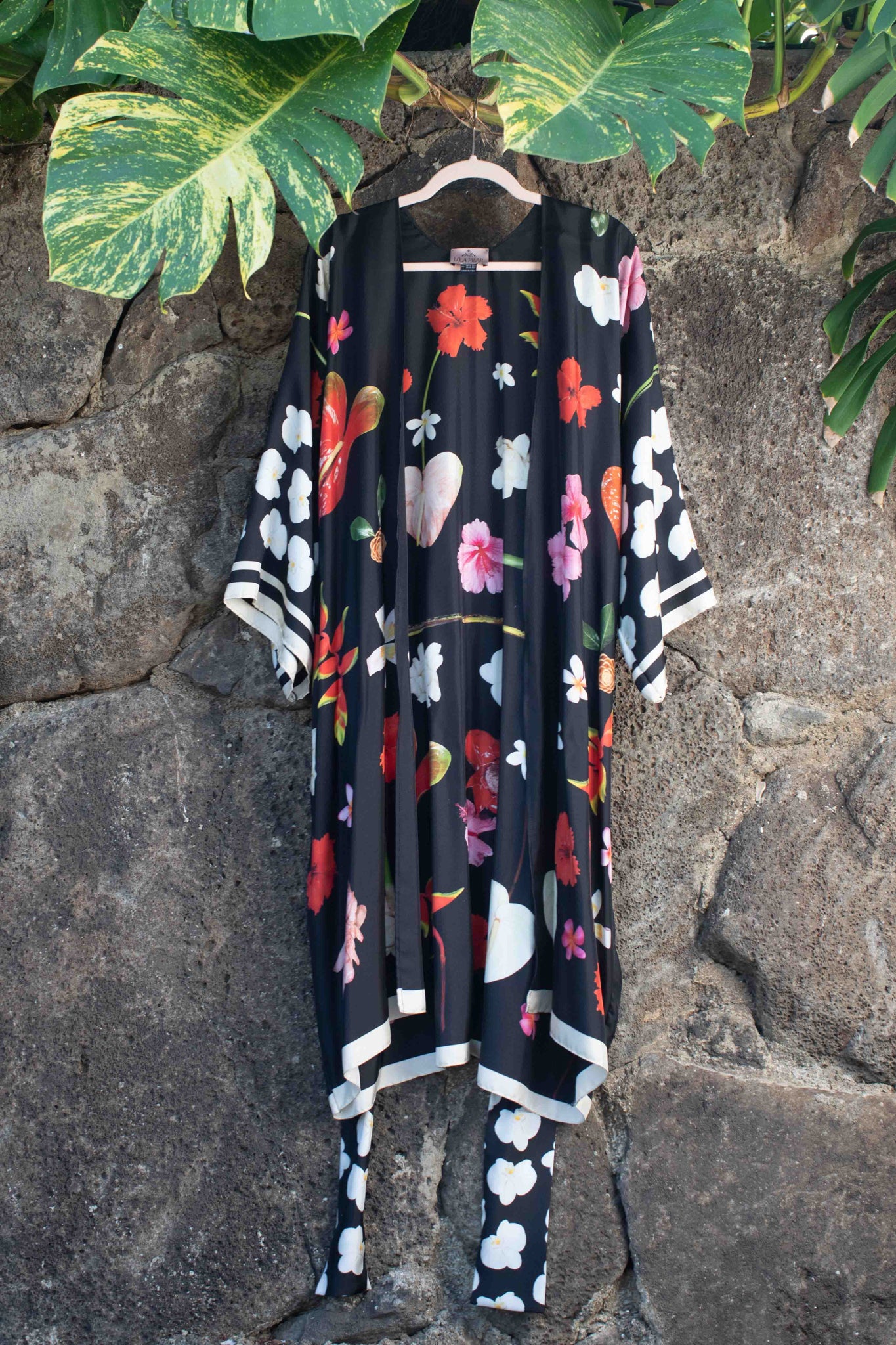 Luxury island evening robe in flowing black silk with sophisticated Hawaiian floral motifs and elegant resort-inspired styling.