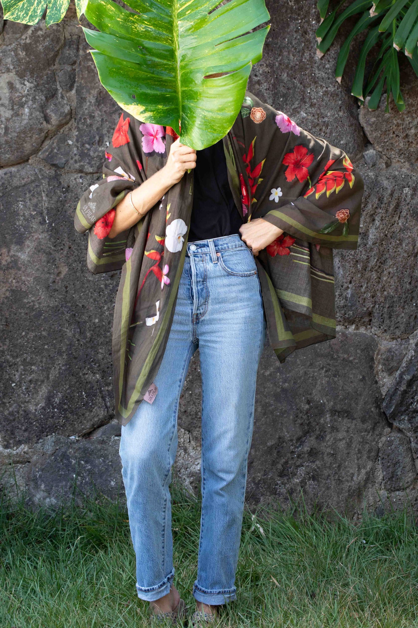 Hawaiian floral wrap with moss green background showcasing hibiscus blooms, hanging heliconia, banana flowers, and plumeria in vibrant tropical shades.