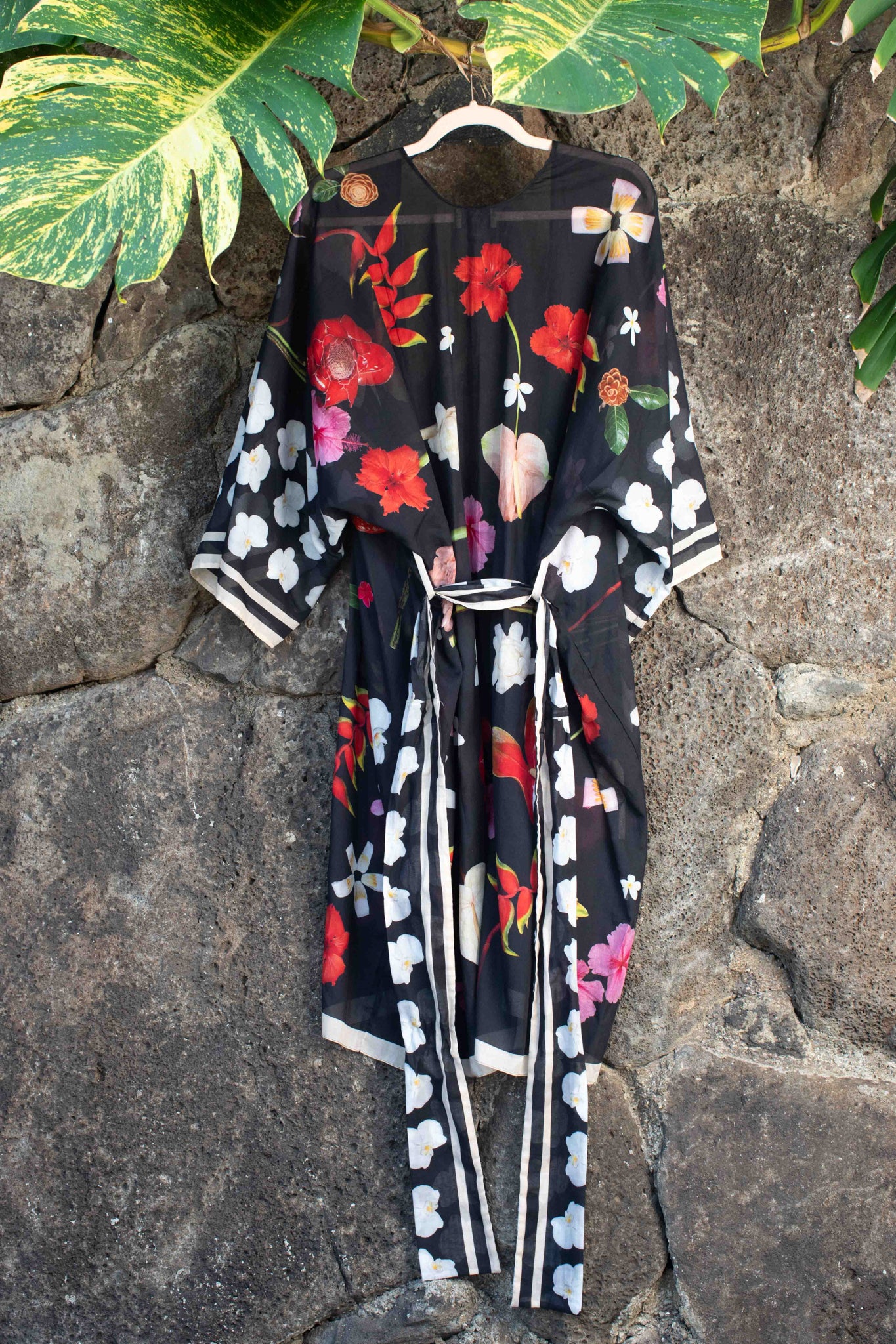 Resort-style black cotton kimono featuring colorful Hawaiian floral artwork with hibiscus, plumeria, and tropical blooms for elevated vacation dressing.