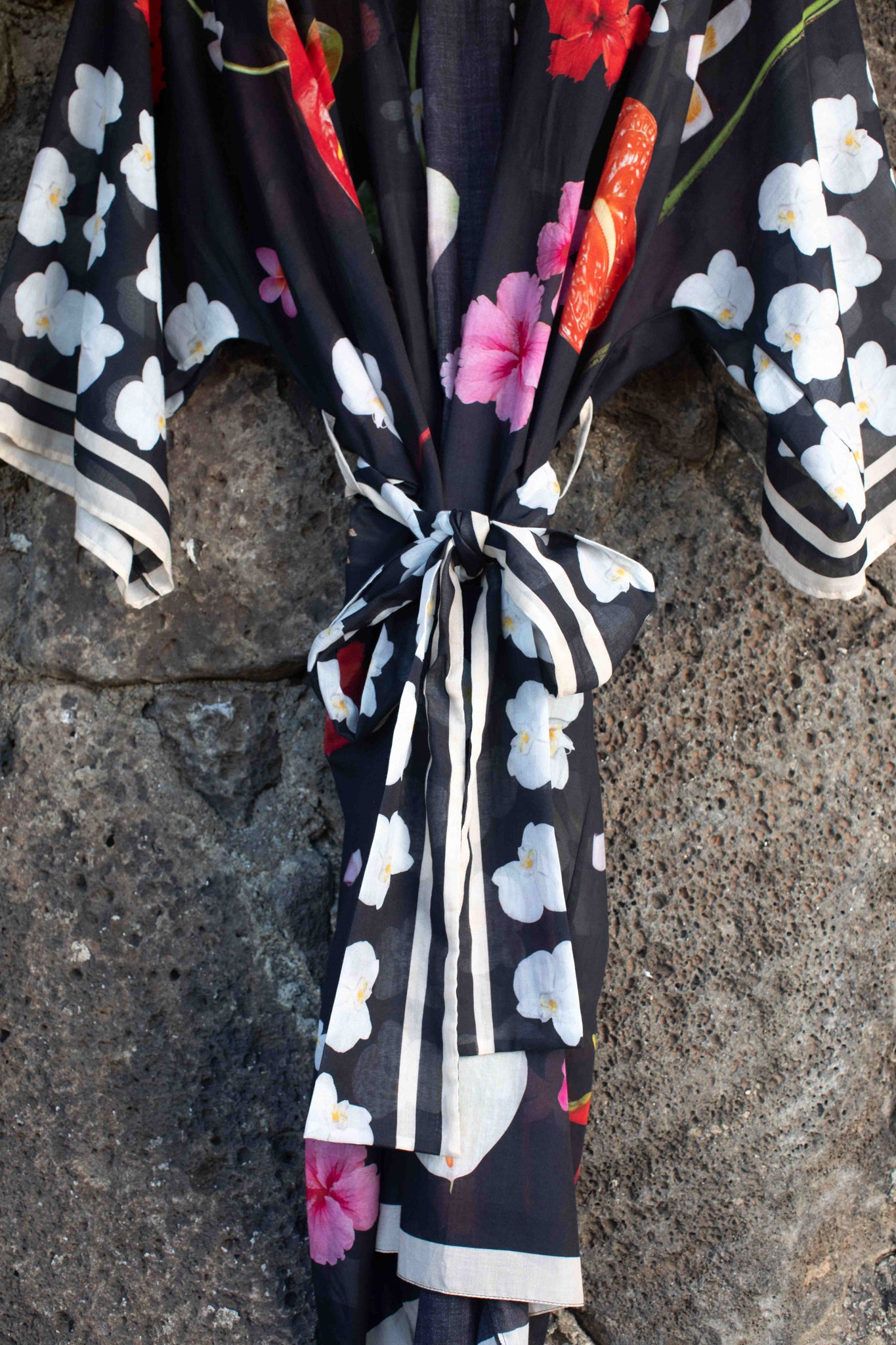 Tropical botanical cotton robe with rich black backdrop and striking floral print in pink, yellow, red, and white by Lola Pilar, made in Italy.