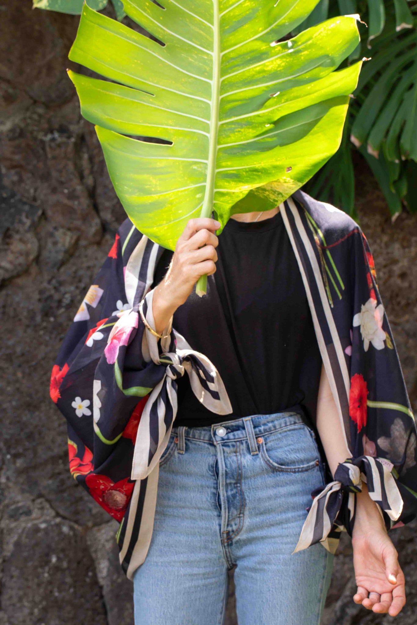 Tropical travel scarf by Lola Pilar featuring a black background with pink, yellow, red, and white Hawaiian floral prints, made in Italy and designed in Hawaii.