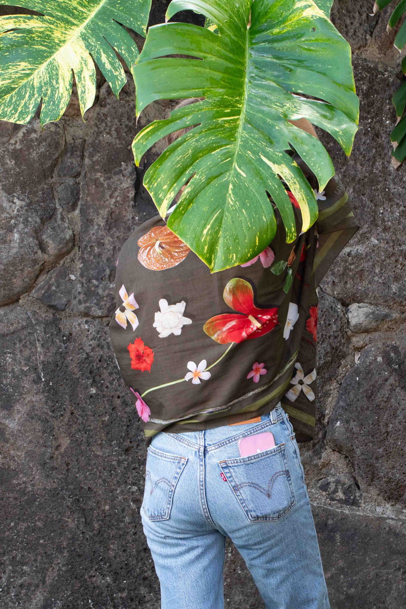 Tropical travel scarf by Lola Pilar featuring a moss green background with pink, yellow, red, and white Hawaiian floral prints, made in Italy and designed in Hawaii.