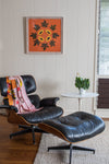 A bright orange photograph with papaya and payapa leaves graces the white walls in this mid-century themed Hawaiian home.