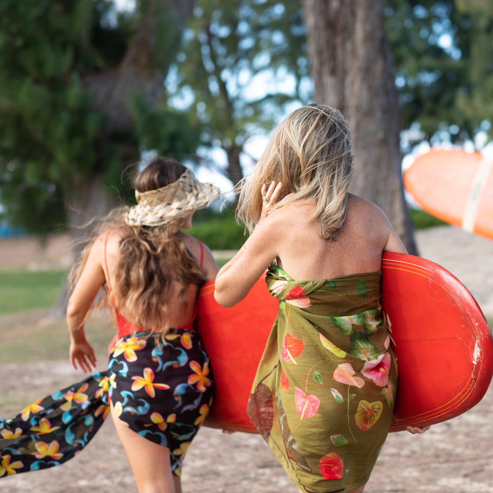 woman hitting the beach with their lola pilar hawaii cotton sarongs to go surfing in kailua