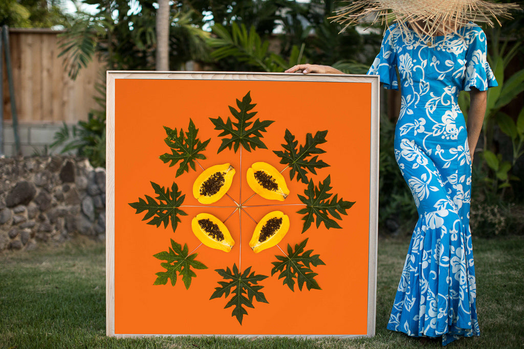 Woman in a hawaiian mumu holding a large 4ftx4ft orange print called Papaya Sunrise inspired by the Hawaiian quilt
